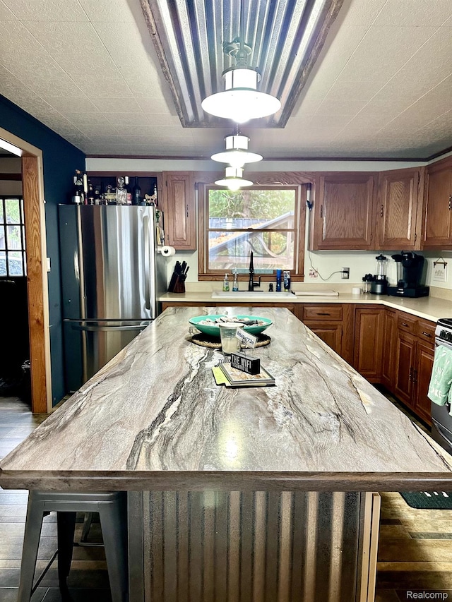 24579 US Highway 23 N, Ocqueoc, MI 49759 - kitchen with freestanding refrigerator, plenty of natural light, a center island, and brown cabinets