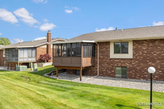 679 Waterview Ct SW, Grandville, MI 49418 - back of property with a sunroom, a lawn, brick siding, and a chimney