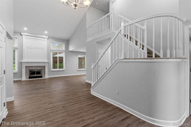 2048 Mayfair Dr, White Lake, MI 48383 - unfurnished living room featuring stairs, high vaulted ceiling, wood finished floors, a glass covered fireplace, and a chandelier