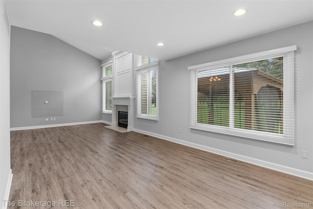 2048 Mayfair Dr, White Lake, MI 48383 - unfurnished living room with wood finished floors, healthy amount of natural light, a fireplace with flush hearth, recessed lighting, and vaulted ceiling