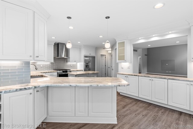 2048 Mayfair Dr, White Lake, MI 48383 - kitchen featuring stainless steel appliances, wall chimney range hood, white cabinetry, decorative backsplash, and wood finished floors