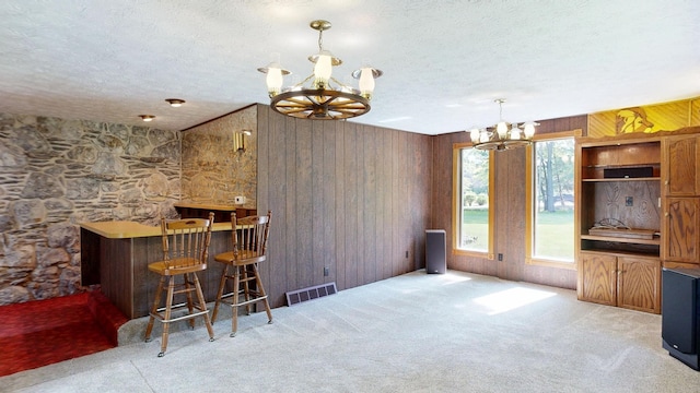 5724 E Townline Rd, Birch Run, MI 48415 - indoor dry bar featuring a chandelier, a textured ceiling, carpet, wood walls, and decorative light fixtures