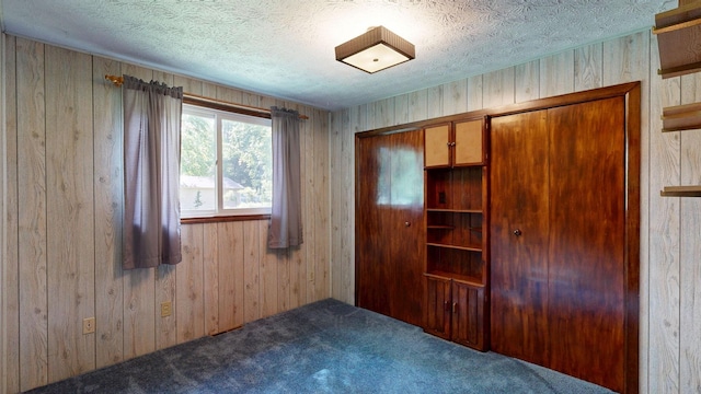 5724 E Townline Rd, Birch Run, MI 48415 - unfurnished bedroom with carpet floors, wooden walls, a closet, and a textured ceiling