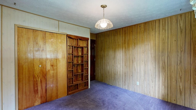 5724 E Townline Rd, Birch Run, MI 48415 - unfurnished bedroom featuring carpet floors, wooden walls, a textured ceiling, and a closet