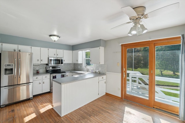 15730 Cedar Springs Ave NE, Cedar Springs, MI 49319 - kitchen with stainless steel appliances, a peninsula, wainscoting, light wood-style flooring, and white cabinets