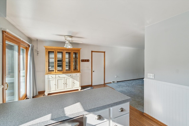 15730 Cedar Springs Ave NE, Cedar Springs, MI 49319 - kitchen featuring wainscoting, ceiling fan, glass insert cabinets, and white cabinetry