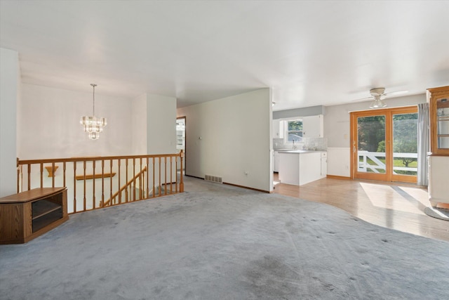 15730 Cedar Springs Ave NE, Cedar Springs, MI 49319 - unfurnished living room featuring light carpet, a chandelier, and ceiling fan