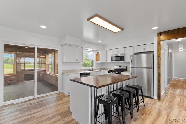 6027 Onsted Hwy, Onsted, MI 49265 - kitchen featuring stainless steel appliances, butcher block counters, a breakfast bar area, white cabinetry, and light wood-style flooring