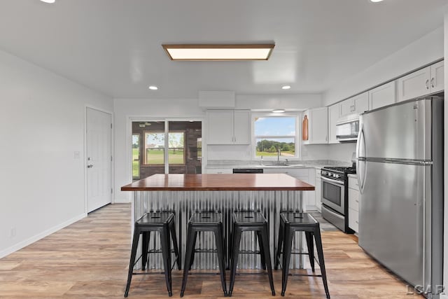 6027 Onsted Hwy, Onsted, MI 49265 - kitchen with appliances with stainless steel finishes, a kitchen island, a kitchen bar, white cabinets, and butcher block countertops