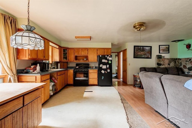 2190 S Coleman Rd, Shepherd, MI 48883 - kitchen with black appliances, brown cabinets, open floor plan, light wood-type flooring, and hanging light fixtures