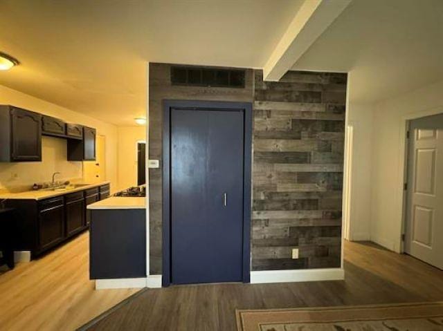 3148 Woodrow Ave, Flint, MI 48506 - kitchen featuring light wood-style floors, light countertops, beam ceiling, dark brown cabinetry, and gas cooktop