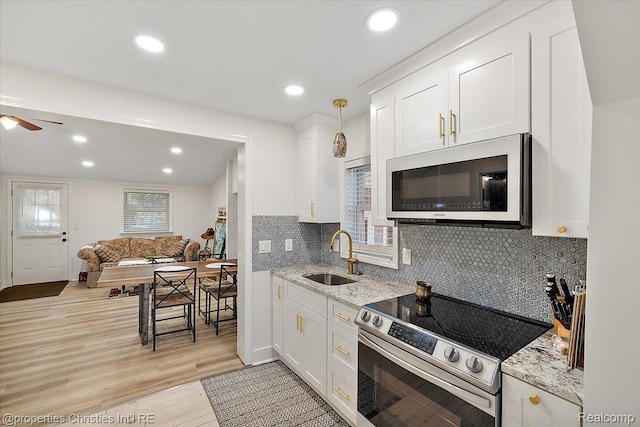 2231 N St, Milford, MI 48380 - kitchen with stainless steel electric stove, white cabinetry, light wood-style floors, decorative backsplash, and recessed lighting