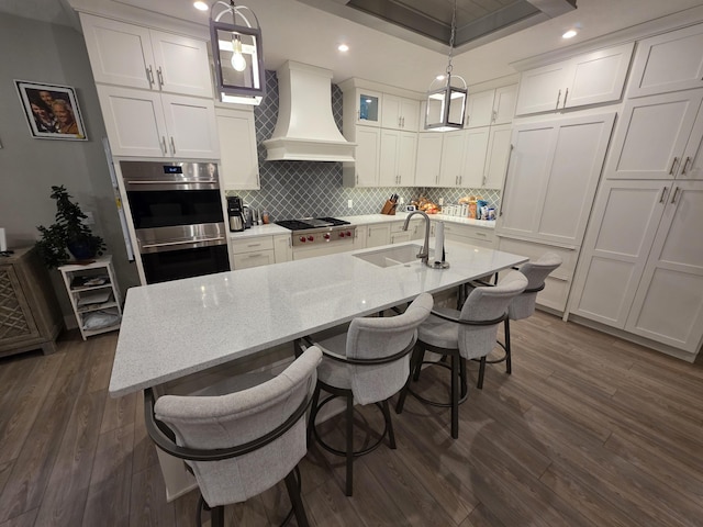 3076 Brayridge Dr, Jenison, MI 49428 - kitchen with premium range hood, appliances with stainless steel finishes, decorative backsplash, a breakfast bar, and white cabinets