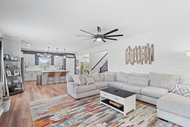 14846 Portage Rd, Vicksburg, MI 49097 - living room featuring light wood-style floors, crown molding, a ceiling fan, stairs, and wooden walls