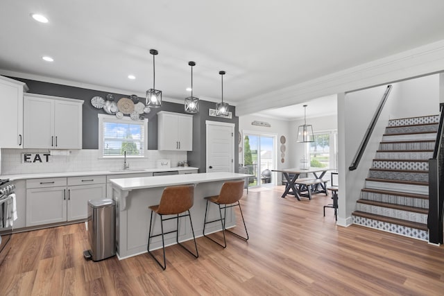 14846 Portage Rd, Vicksburg, MI 49097 - kitchen with a center island, tasteful backsplash, a breakfast bar, light countertops, and light wood-style floors
