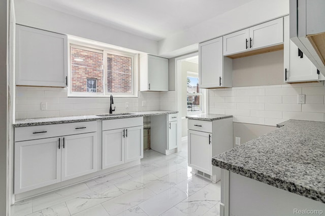 5766 Nottingham Rd, Detroit, MI 48224 - kitchen with light marble finish floors, light stone countertops, tasteful backsplash, and white cabinetry