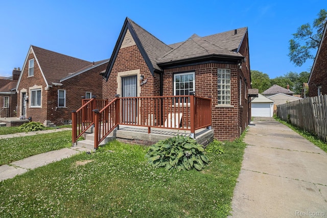 5766 Nottingham Rd, Detroit, MI 48224 - tudor house featuring brick siding, a detached garage, roof with shingles, an outdoor structure, and a wooden deck