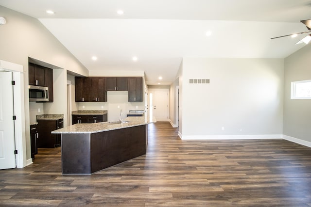 11449 Hidden Oaks Dr, Clio, MI 48420 - kitchen featuring stainless steel microwave, vaulted ceiling, dark brown cabinetry, an island with sink, and a ceiling fan