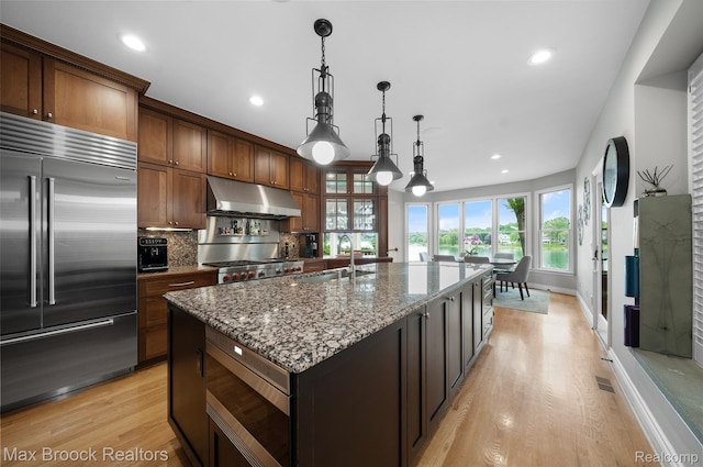 6510 Commerce Rd, West Bloomfield, MI 48324 - kitchen featuring built in appliances, under cabinet range hood, light wood-style flooring, dark stone countertops, and recessed lighting