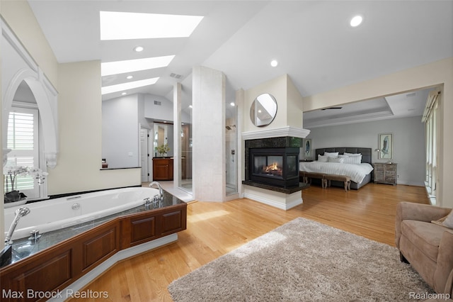 6510 Commerce Rd, West Bloomfield, MI 48324 - ensuite bathroom with a stall shower, a garden tub, wood finished floors, vaulted ceiling, and a multi sided fireplace