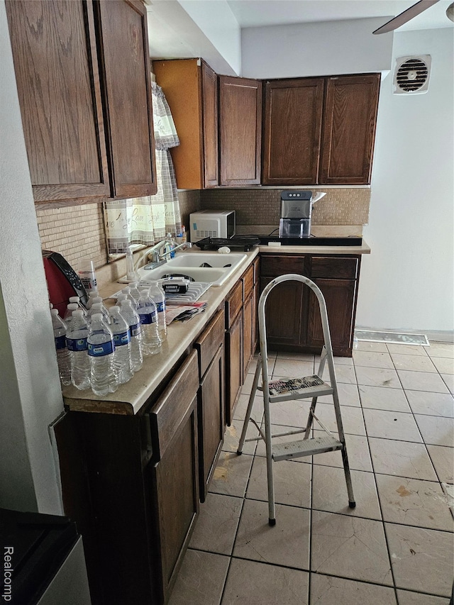 6010 Marja St, Flint, MI 48505 - kitchen featuring tasteful backsplash, light countertops, light tile patterned floors, and dark brown cabinets