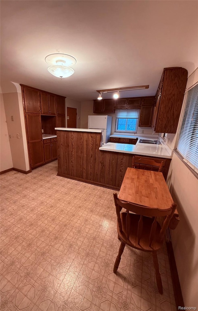 906 W Burnside St, Caro, MI 48723 - kitchen with a peninsula, light countertops, and freestanding refrigerator
