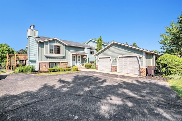 5049 Stauffer Ave SE, Grand Rapids, MI 49508 - split foyer home with board and batten siding, brick siding, a chimney, a garage, and an outbuilding