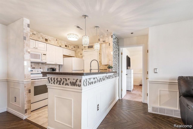 37510 Jefferson Unit 203, Harrison Township, MI 48045 - kitchen with white appliances, dark countertops, a peninsula, decorative backsplash, and hanging light fixtures