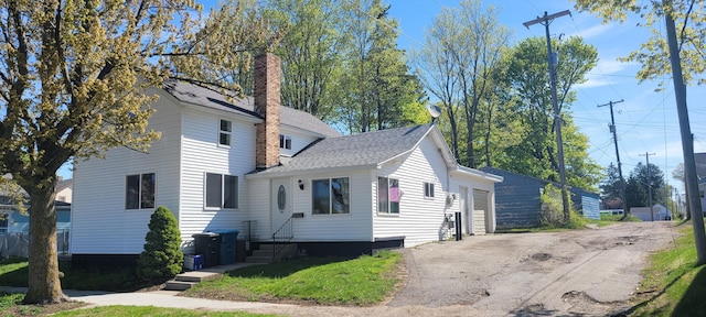 403 S Emily St, Ludington, MI 49431 - view of front of house with a garage, a chimney, and roof with shingles