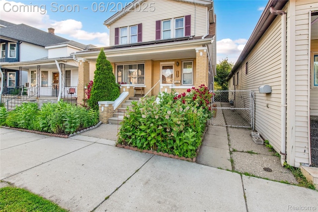 2429 Holmes St, Hamtramck, MI 48212 - traditional home featuring a porch, brick siding, and a gate