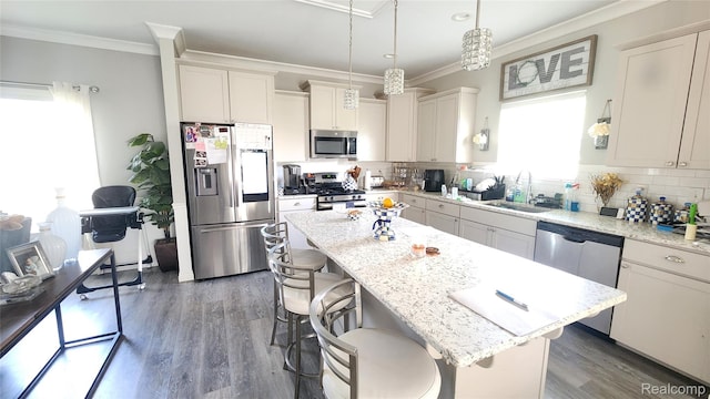 2315 Willow Ln, Grand Blanc, MI 48439 - kitchen featuring appliances with stainless steel finishes, wood finished floors, a breakfast bar area, a center island, and ornamental molding