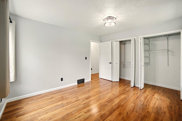 2350 155th Ave, Morley, MI 49336 - unfurnished bedroom with multiple closets, light wood-style floors, and a textured ceiling