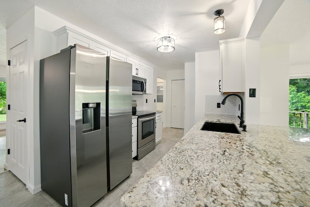 2350 155th Ave, Morley, MI 49336 - kitchen with appliances with stainless steel finishes, white cabinets, tasteful backsplash, and light stone countertops