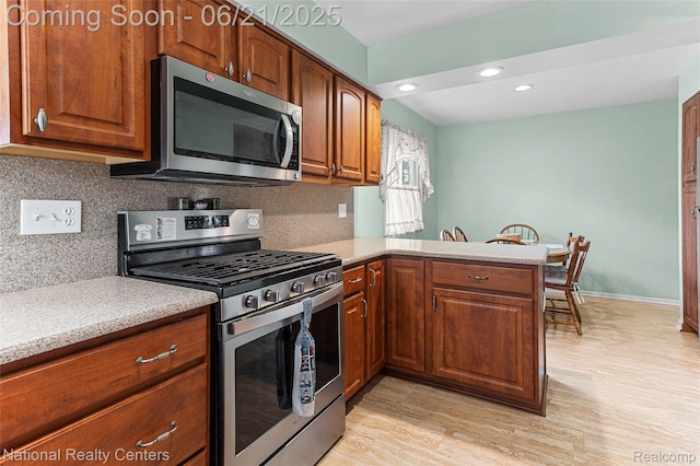 1306 Bishops Ter, Wixom, MI 48393 - kitchen with stainless steel appliances, light countertops, backsplash, a peninsula, and brown cabinetry