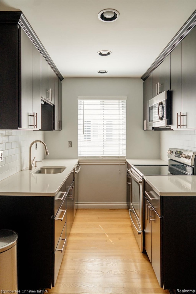 1715 E 14 Mile Rd, Birmingham, MI 48009 - kitchen with stainless steel appliances, light wood finished floors, backsplash, dark cabinets, and light countertops