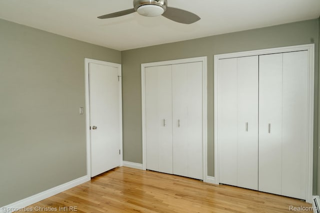 1715 E 14 Mile Rd, Birmingham, MI 48009 - unfurnished bedroom featuring multiple closets, baseboard heating, light wood-style flooring, and ceiling fan