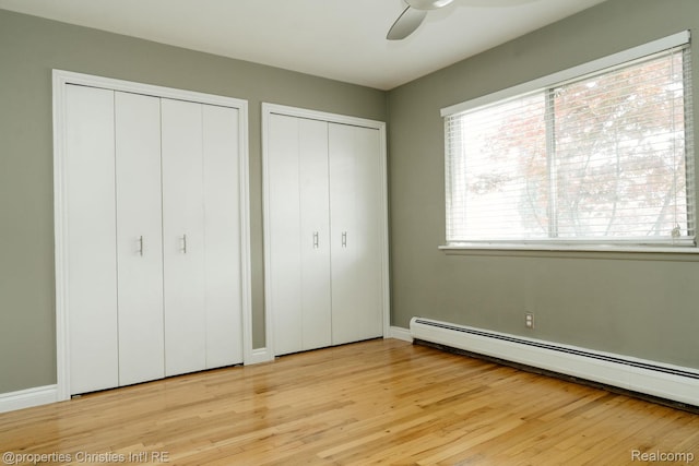1715 E 14 Mile Rd, Birmingham, MI 48009 - unfurnished bedroom featuring a baseboard radiator, multiple closets, light wood-style flooring, and a ceiling fan