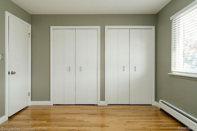 1715 E 14 Mile Rd, Birmingham, MI 48009 - unfurnished bedroom with a baseboard radiator, two closets, and light wood-style flooring
