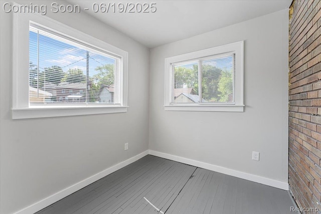 243 2nd St, Brownstown, MI 48192 - spare room with dark wood-type flooring and brick wall