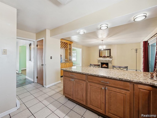 664 Buckingham Ave, Lincoln Park, MI 48146 - kitchen with light tile patterned floors, a lit fireplace, brown cabinetry, and light stone counters