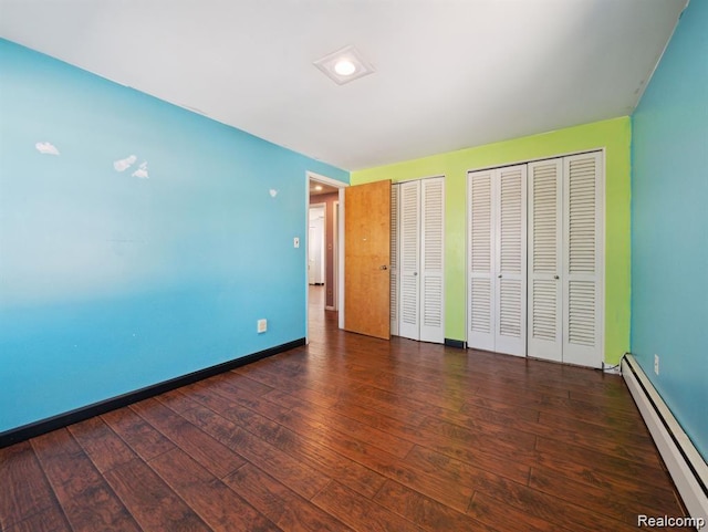 664 Buckingham Ave, Lincoln Park, MI 48146 - unfurnished bedroom featuring a baseboard heating unit, two closets, and hardwood / wood-style flooring