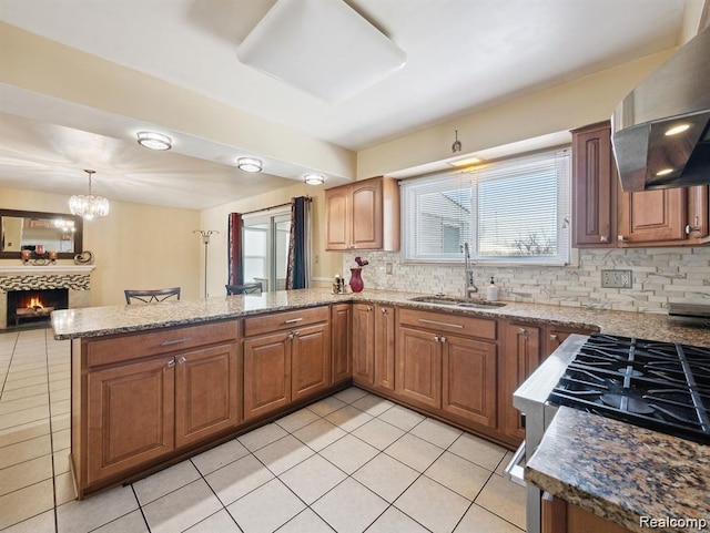 664 Buckingham Ave, Lincoln Park, MI 48146 - kitchen with wall chimney exhaust hood, light tile patterned floors, a peninsula, backsplash, and a warm lit fireplace