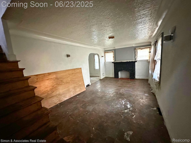 20203 Hull St, Detroit, MI 48203 - unfurnished living room featuring arched walkways, a fireplace, a textured ceiling, and stairs