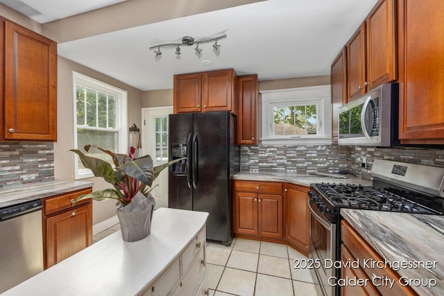 1328 Bemis St SE, Grand Rapids, MI 49506 - kitchen with appliances with stainless steel finishes, tasteful backsplash, light tile patterned flooring, light countertops, and brown cabinetry