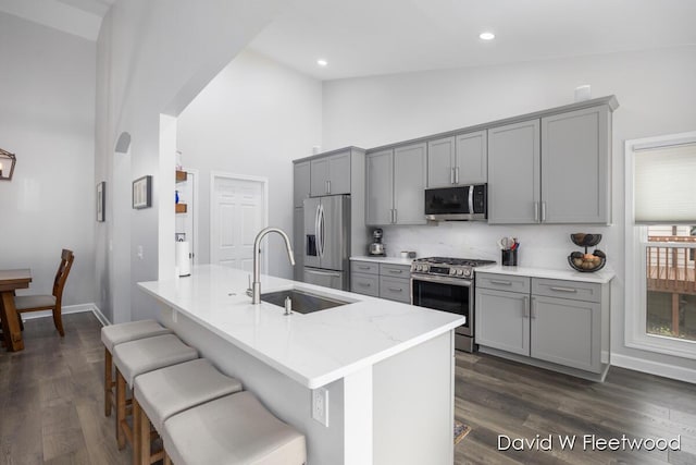 6935 Fairway Vista Dr SE, Caledonia, MI 49316 - kitchen with appliances with stainless steel finishes, gray cabinetry, high vaulted ceiling, tasteful backsplash, and dark wood-style flooring