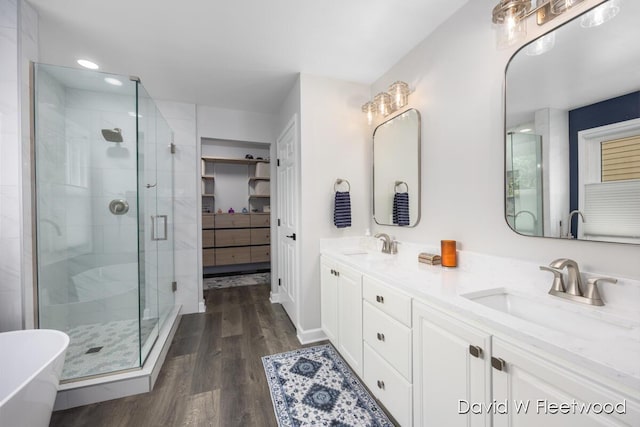 6935 Fairway Vista Dr SE, Caledonia, MI 49316 - bathroom featuring a stall shower, double vanity, wood finished floors, a freestanding tub, and recessed lighting