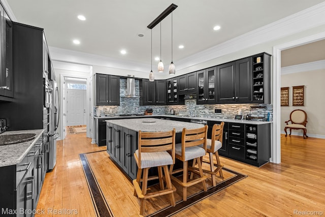 5626 Shadow Ln, Bloomfield Hills, MI 48302 - kitchen with wall chimney range hood, dark cabinetry, a kitchen island, ornamental molding, and decorative backsplash
