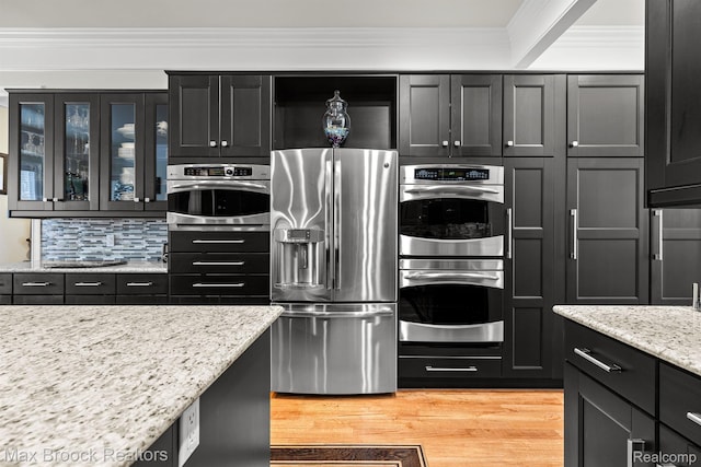 5626 Shadow Ln, Bloomfield Hills, MI 48302 - kitchen with stainless steel appliances, light wood-type flooring, ornamental molding, light stone counters, and glass insert cabinets