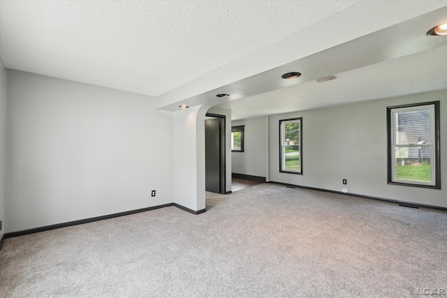605 Oak St, Hudson, MI 49247 - spare room featuring light colored carpet, a textured ceiling, and arched walkways