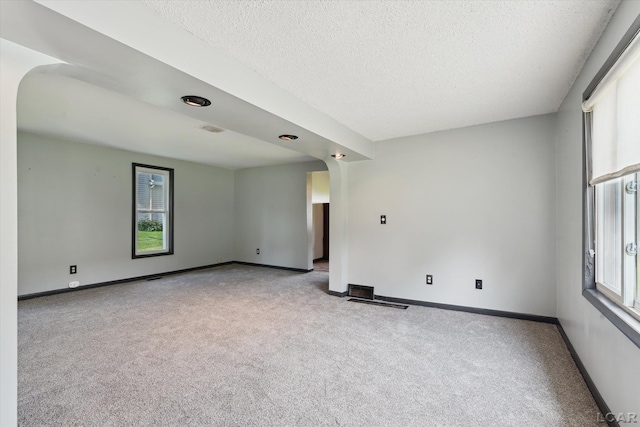 605 Oak St, Hudson, MI 49247 - carpeted spare room with plenty of natural light, arched walkways, and a textured ceiling